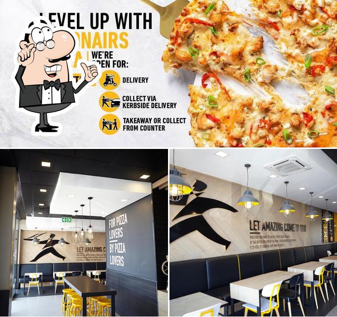 Take a look at the photo showing interior and pizza at Debonairs Pizza