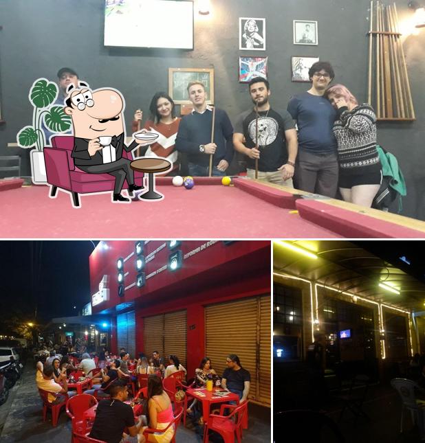 Sente em uma das mesas no Escritório Bar