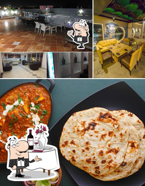Check out the picture showing dining table and pizza at Dawat Rooftop Restro & Bar