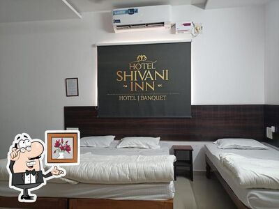 Take a seat at one of the tables at Shivani Inn Hotel & Banquet